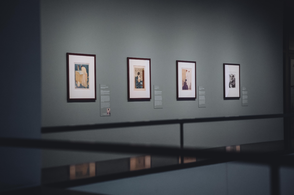 De 4 prents van Mary Cassatt op een rij tegen een grijze muur.